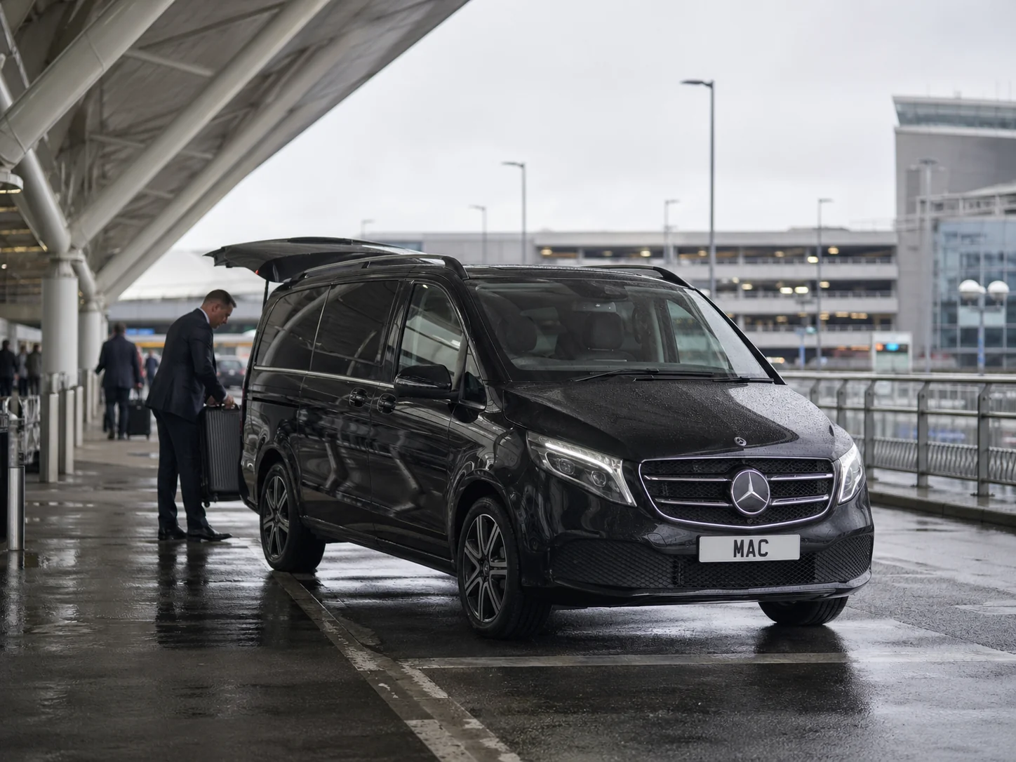 Manchester Airport half-day chauffeur hire with a black Mercedes V-Class and professional chauffeur collecting a passenger at the terminal